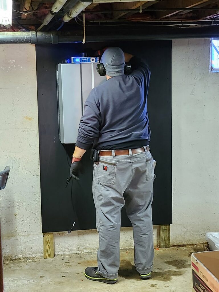 A technician installing a Rinnai tankless water heater for Derry Plumbing & Heating in Derry, NH.