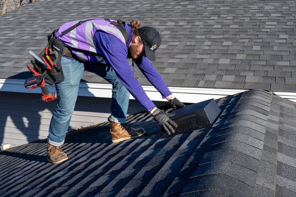 A technician installing a roof vent cover for wildlife exclusion at Abra Kadabra Pest and Wildlife in Forest Lake, MN.