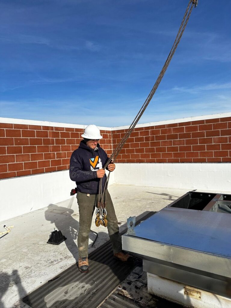 A technician in a hard hat installing a rooftop HVAC unit for Boise Valley Heating & Air in Meridian, ID