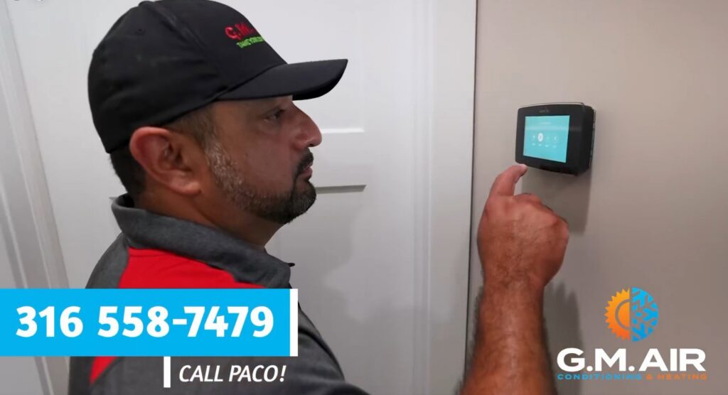 A technician installing or setting up a smart thermostat for G.M. AIR Conditioning & Heating in Wichita, KS.