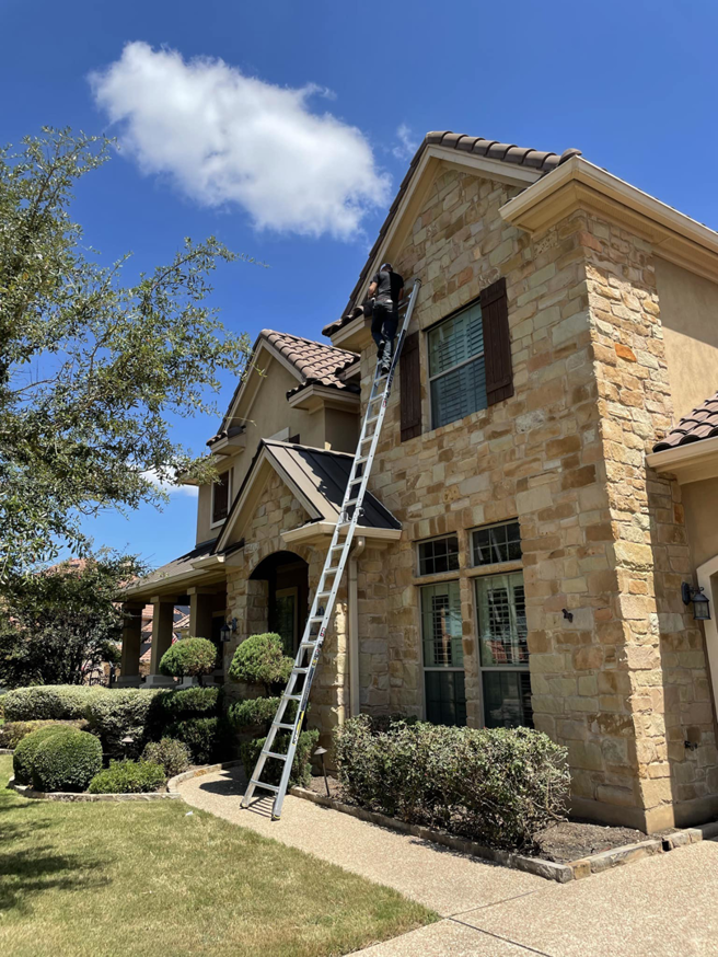 A technician on a ladder inspecting or treating a residential house for pests by CARE PEST PROS in Austin, TX.