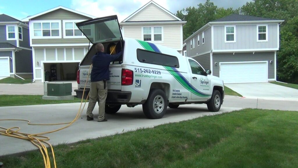 A technician loading equipment into a branded service truck for Springer Professional Home Services in Des Moines, IA.