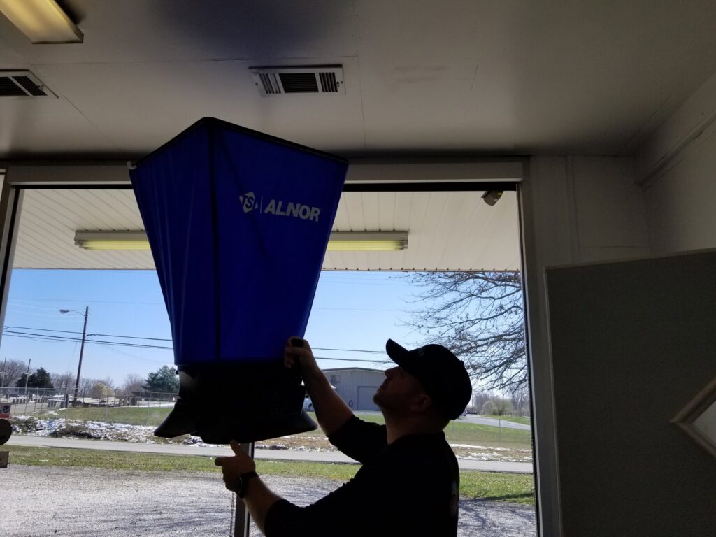 A technician from Madison HVAC/R, Inc measuring airflow from a ceiling vent with an Alnor capture hood in Richmond, KY.