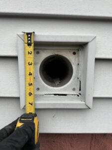 A technician measuring a vent opening on a house for pest exclusion services by Pike Creek Exterminating in Kenosha, WI.