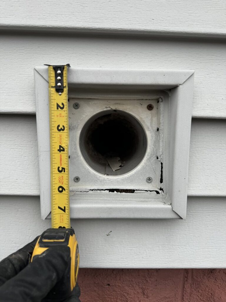 A technician measuring a vent opening on a house for pest exclusion services by Pike Creek Exterminating in Kenosha, WI.