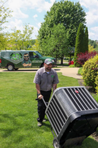 A technician moving an outdoor AC unit for installation or service by Ash Plumbing, Drain & Sewer in Akron, OH.