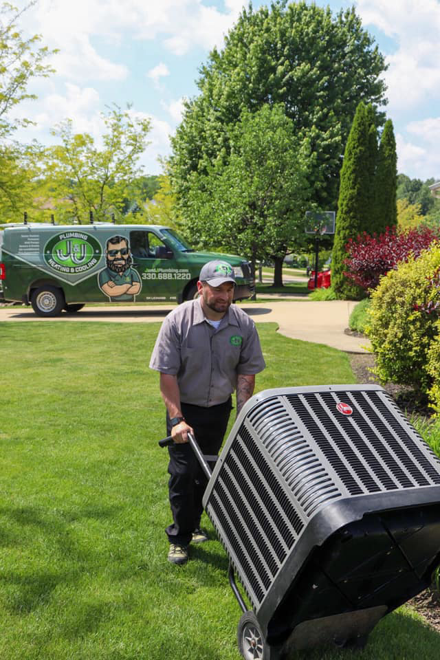 A technician moving an outdoor AC unit for installation or service by Ash Plumbing, Drain & Sewer in Akron, OH.