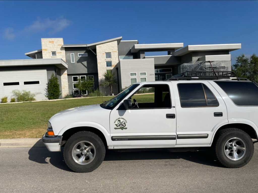 A technician on a ladder inspecting a residential roof for wildlife entry points, provided by Texas Rodent Control in San Antonio, TX.