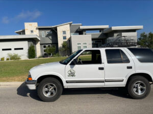 A technician on a ladder inspecting a residential roof for wildlife entry points, provided by Texas Rodent Control in San Antonio, TX.