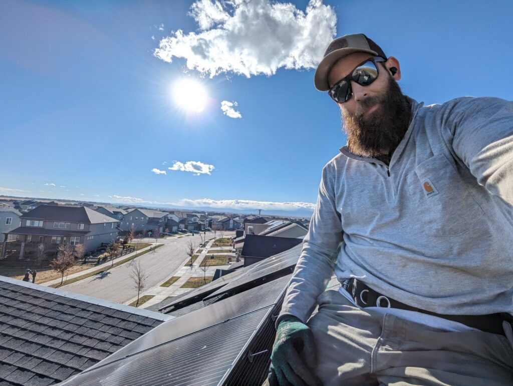 A technician from Elevated Pest Control LLC on a roof, working on solar panel critter exclusion in Berthoud, CO.