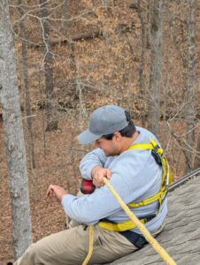 A technician secured with a harness and rope, working on a roof for wildlife exclusion by Direct Pest Solutions Of Georgia, LLC in McDonough, GA.