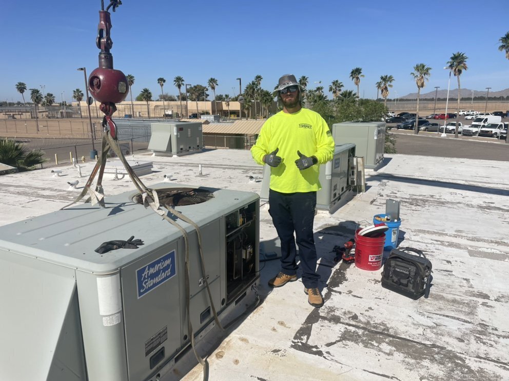 A technician on a rooftop next to a commercial HVAC unit being installed by Mountainside Air in Phoenix, AZ.