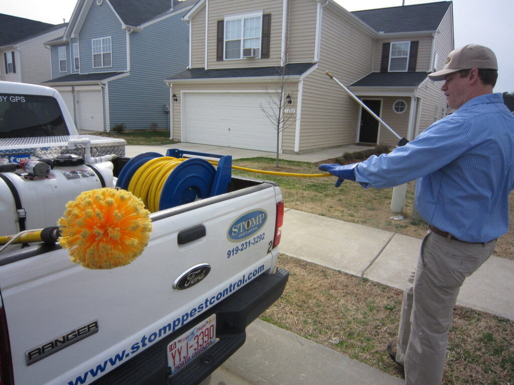 A Stomp Pest Control technician standing next to a service truck, ready for a pest control job in Raleigh, NC.