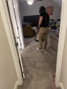 A technician operating a carpet cleaning machine in a residential room, performing carpet contractor services for Pro Clean Group in Knoxville, TN.