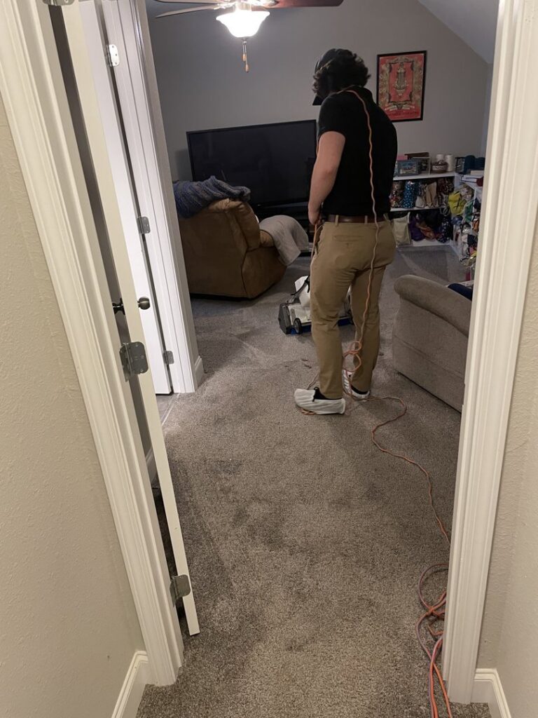 A technician operating a carpet cleaning machine in a residential room, performing carpet contractor services for Pro Clean Group in Knoxville, TN.