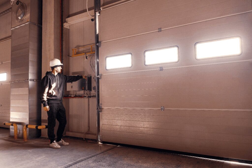 A technician in a hard hat operating a commercial garage door control panel for Fort Wayne Door & Dock, Inc. in Fort Wayne, IN