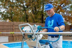 A technician operating pool cleaning equipment next to a pool for Ultra Pool Care Squad of East Chattanooga, TN.
