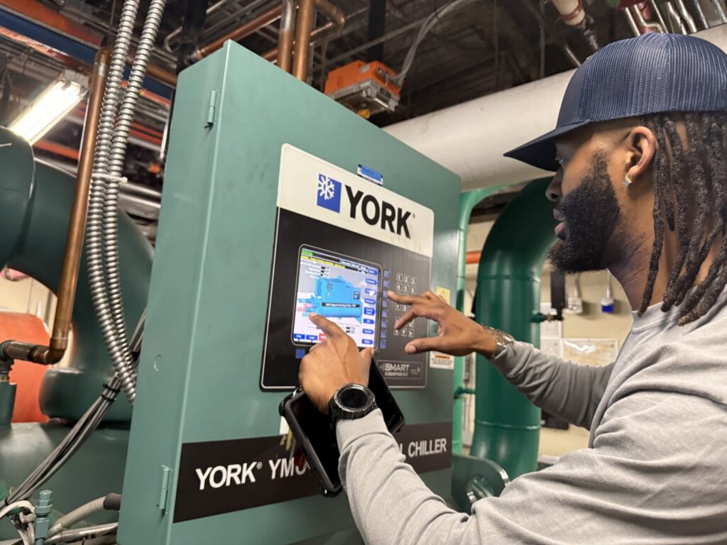 An Interstate AC technician operating the control panel of a large YORK commercial chiller unit in Nashville, TN.
