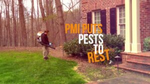 A Pest Management Systems, Inc. technician performing outdoor pest treatment on a residential lawn in Greensboro, NC