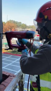 A Smart Solutions Wildlife Removal Specialists technician performing exclusion work with a Hilti tool in Roswell, GA.