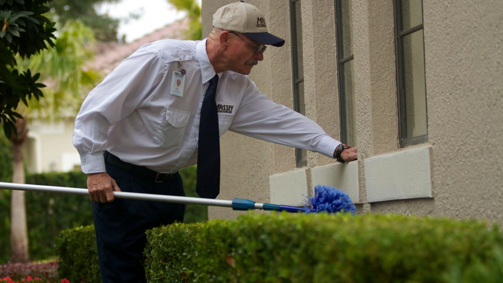 A Massey Services, Inc. technician performing exterior pest control treatment on a building in Melbourne, FL.