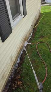 A technician performing exterior pest treatment along a house foundation by Best Termite & Pest Control, Inc. in Manchester, KY.