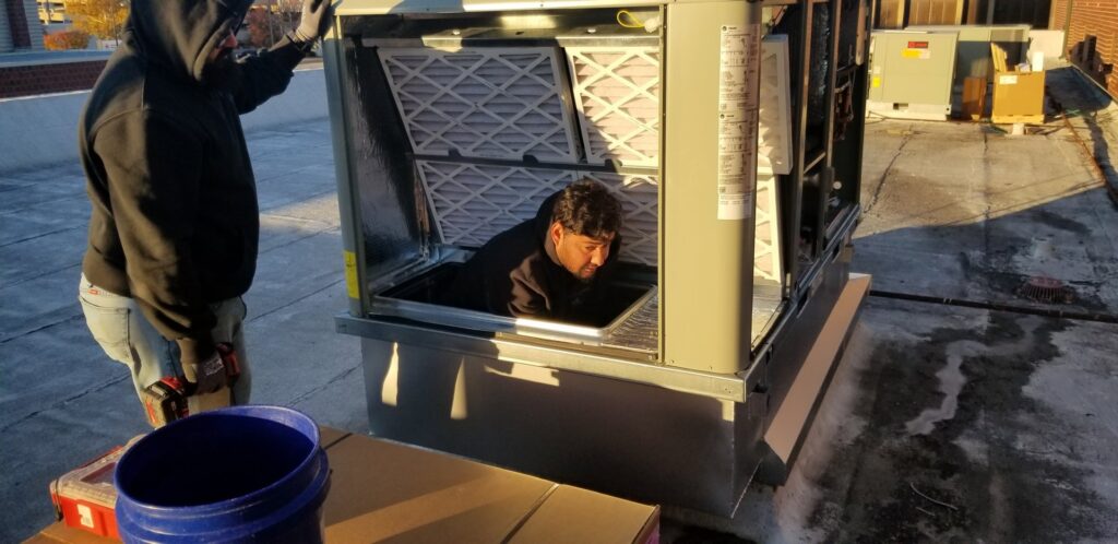A technician performing maintenance inside a commercial rooftop HVAC unit for Frederick Plumbing, Heating & Air Conditioning, Wichita, KS