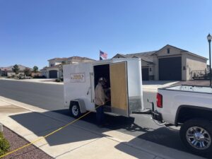 A technician from Reliable pest control solutions performing a pest control service with a hose from the trailer in Hannibal, MO