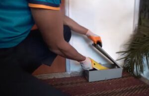 A pest control technician placing a bait station indoors for rodent control services by Rodent Control Cleveland in Cleveland, OH.