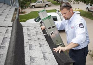 A pest control technician placing a ladder on a roof for an inspection or treatment by American Pest Management in Saint Petersburg, FL.