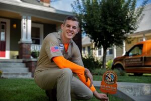 A Mosquito Hunters of Grand Rapids, MI technician placing a pest control yard sign in front of a residential home.