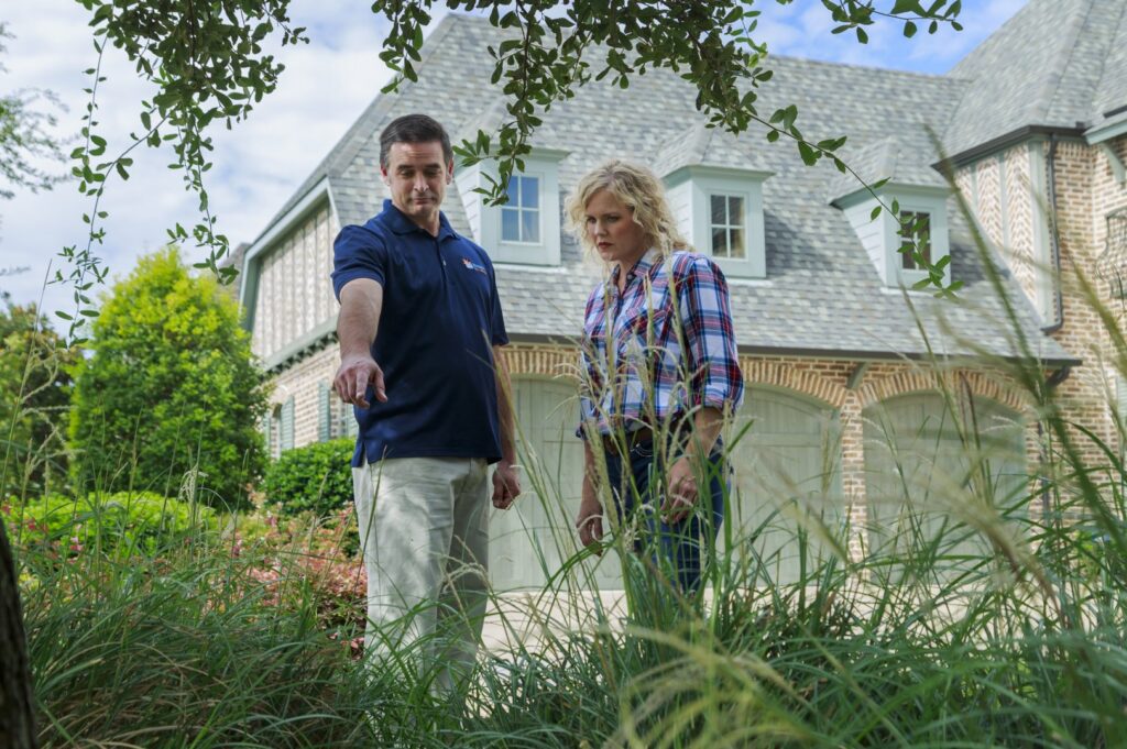 A Berrett Pest Control Denver technician pointing out a pest issue in tall grass to a customer in Denver, CO.