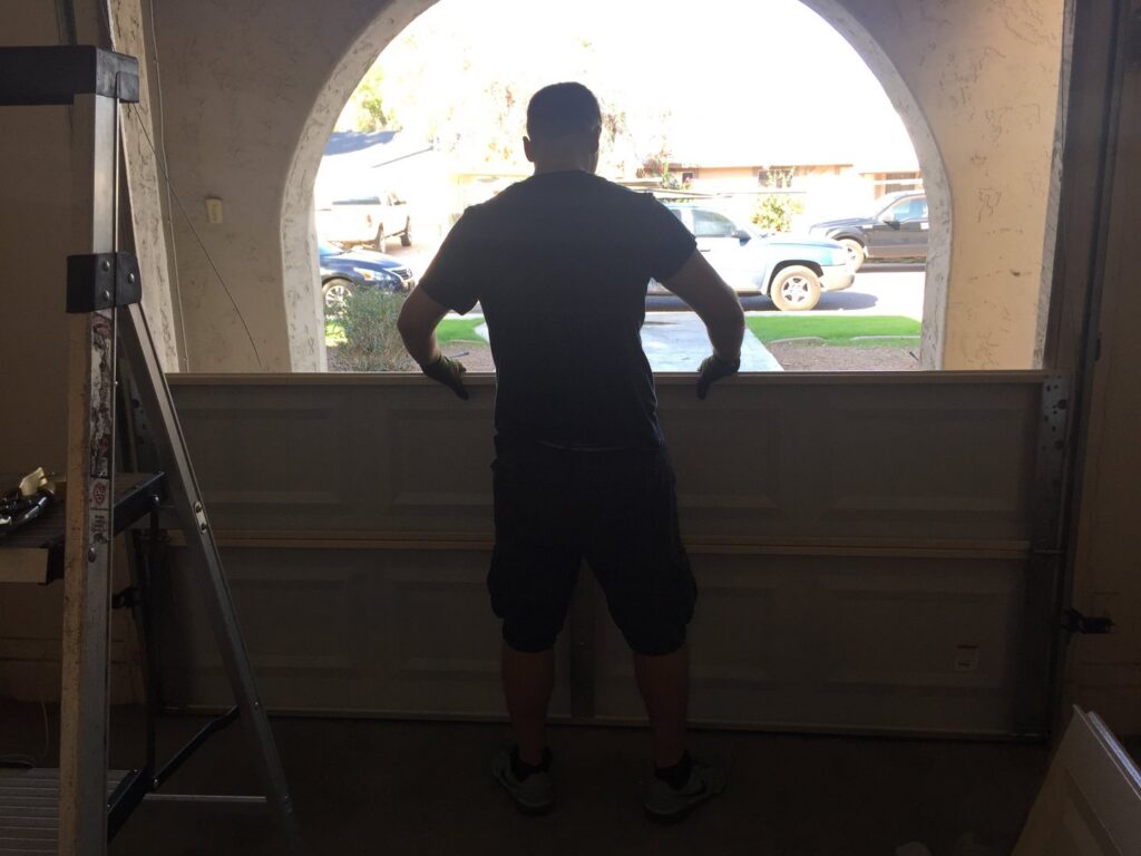 A technician positioning a garage door panel during installation by Nate's Garage Door Repair in Scottsdale, AZ.