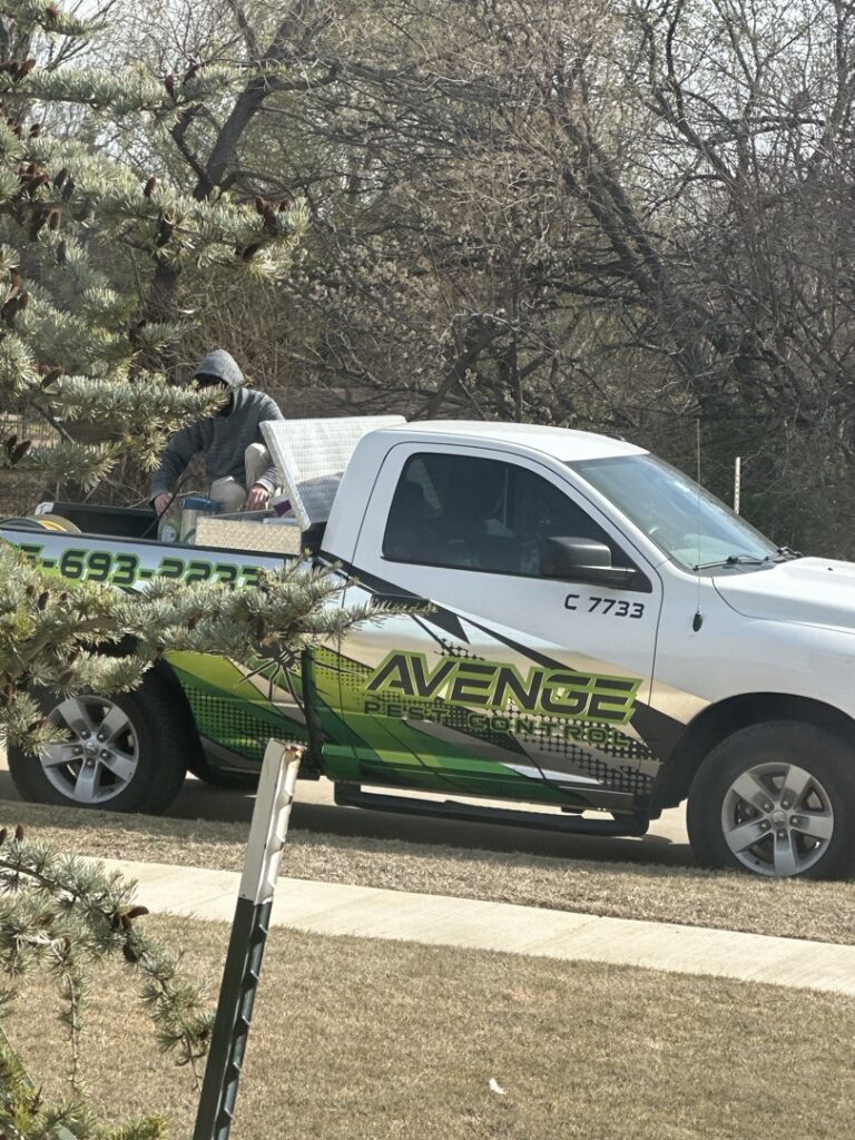 A technician preparing equipment in the back of an Avenge Pest Control truck for a job in Edmond, OK.