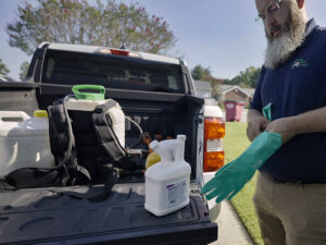 A Pest Magic Pest Control technician putting on gloves, preparing for a pest control job in Forsyth, GA.