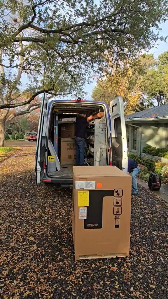 A technician preparing a new gas furnace inside a company van before installation by Harlen Johnson Heating & Air in Dallas, TX.