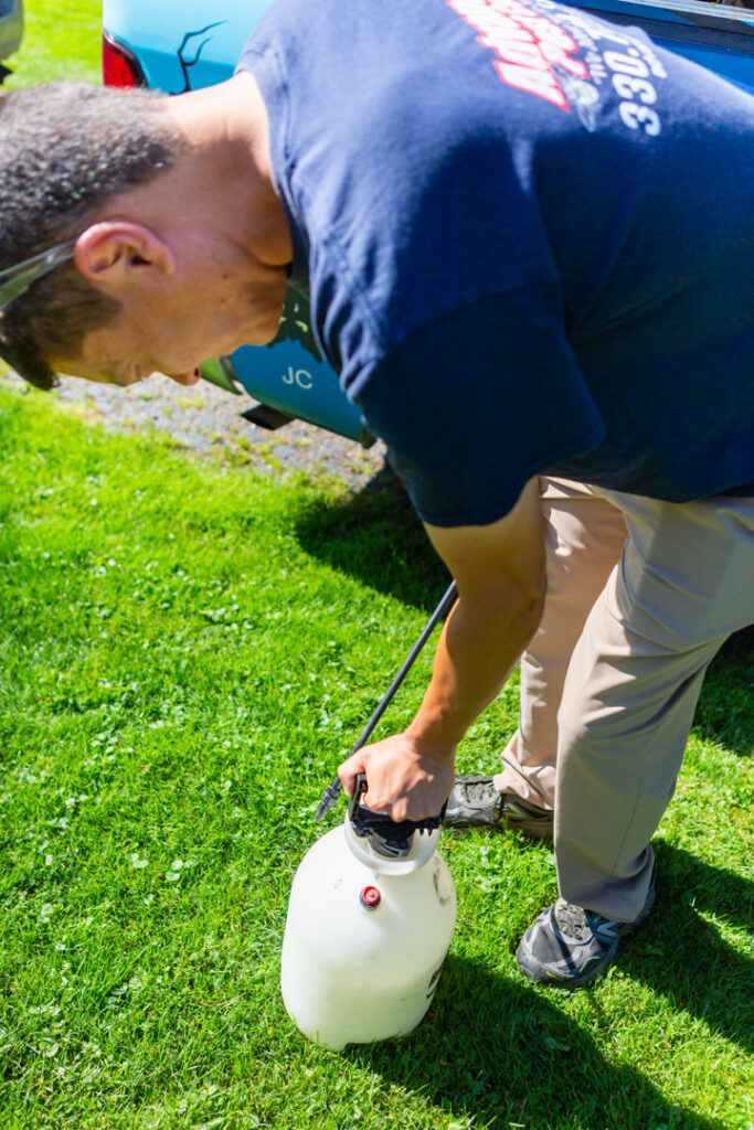 A pest control technician preparing a sprayer for pest treatment services at Advanced Pest Control Solutions in Youngstown, OH.