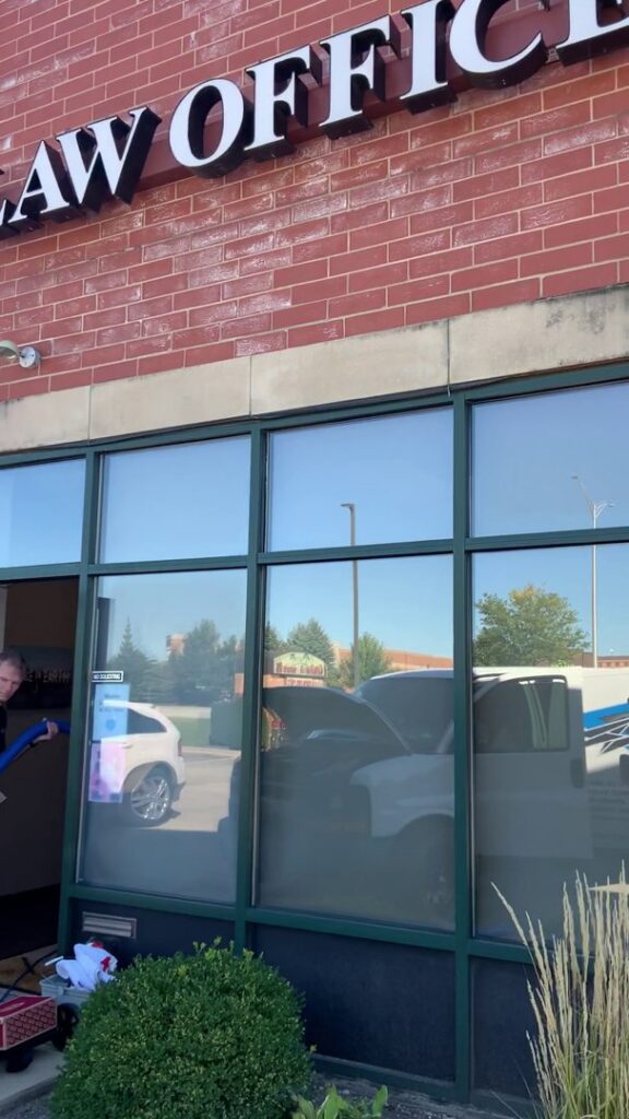 A technician from S&J Carpet Care pulling a cleaning hose into a law office for commercial carpet cleaning in Oswego, IL