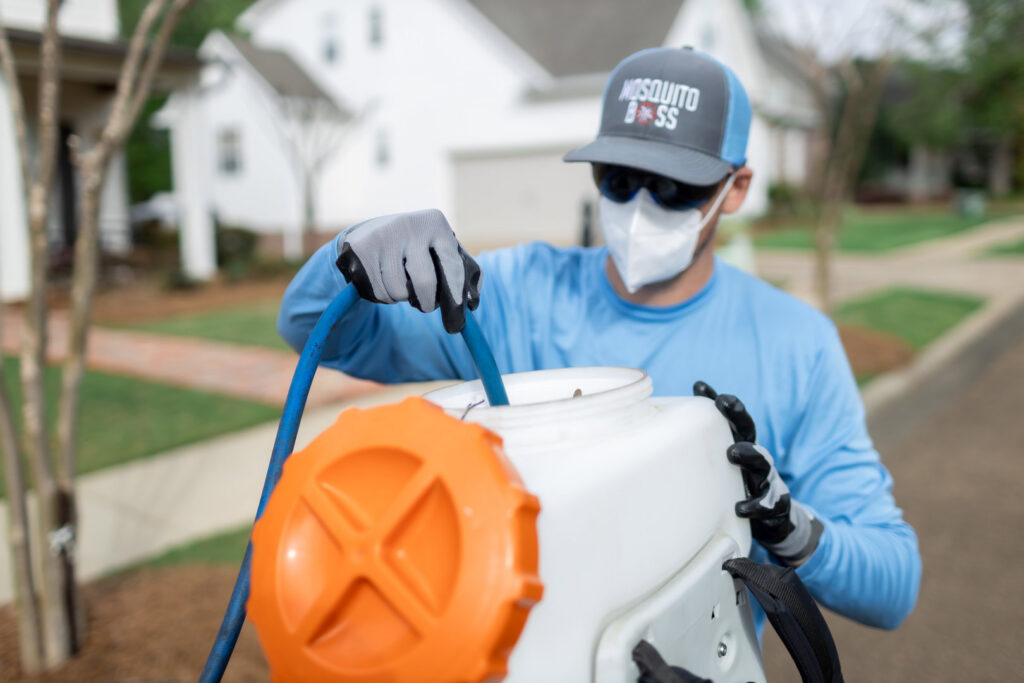 A Mosquito Boss technician refilling a backpack sprayer with pest control solution in Brandon, MS