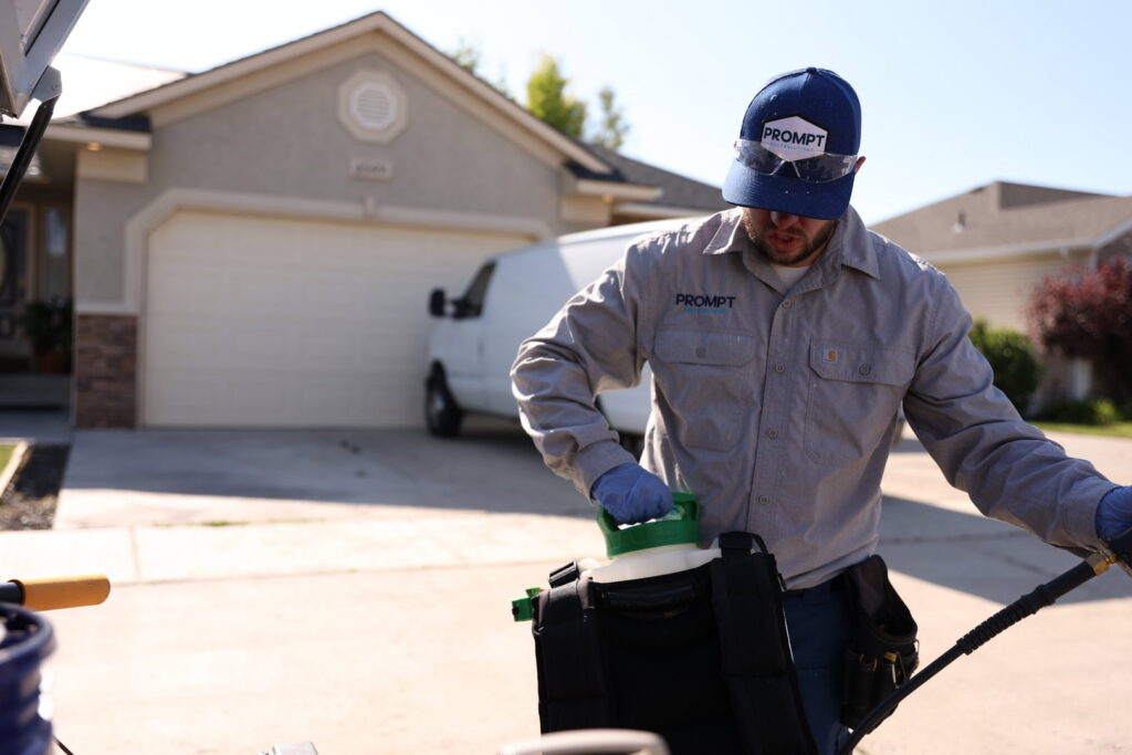A Prompt Pest Solutions technician refilling a backpack sprayer from a container in Pocatello, ID.