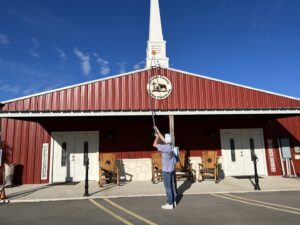 A Blessed Pest Control technician removing spider webs from the exterior of a building in San Antonio, TX