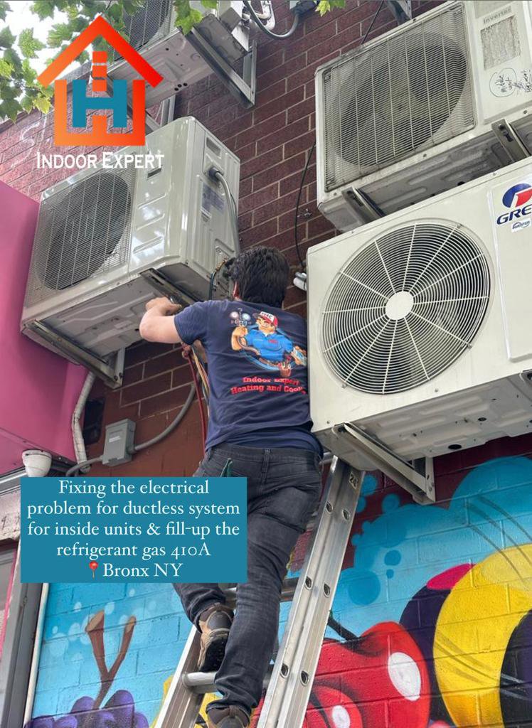 A technician from Indoor Expert Heating & Cooling on a ladder, repairing multiple outdoor ductless mini-split units in Paterson, NJ.