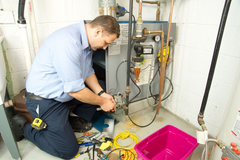A technician repairing a furnace or heating system in a utility room, a service provided by APM Heating and Air Conditioning in Columbia, MO.