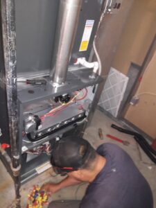 A National Heating & Cooling Company technician repairing furnace wiring and internal components in Lakewood, CO.