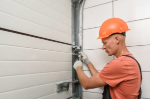 A technician in a hard hat and gloves repairing the mechanism of a garage door for Ins-Garage Door Repair-Burnside Branch in Portland, OR.