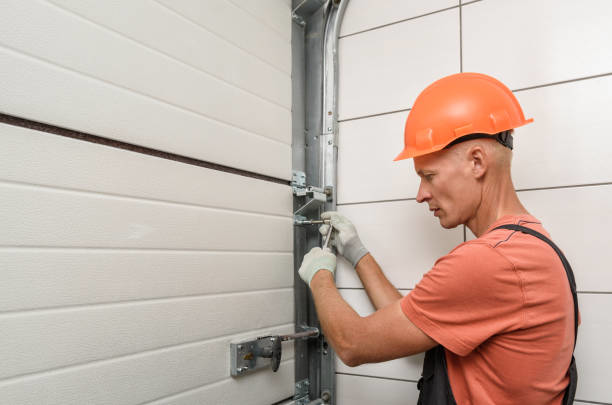 A technician in a hard hat and gloves repairing the mechanism of a garage door for Ins-Garage Door Repair-Burnside Branch in Portland, OR.