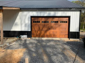 A technician on a ladder repairing a white garage door from the interior at CHS Garage Repair of Seattle, WA.