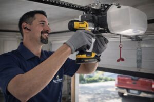 A Baystate Garage Door technician repairing a garage door opener with a drill in Milton, MA.