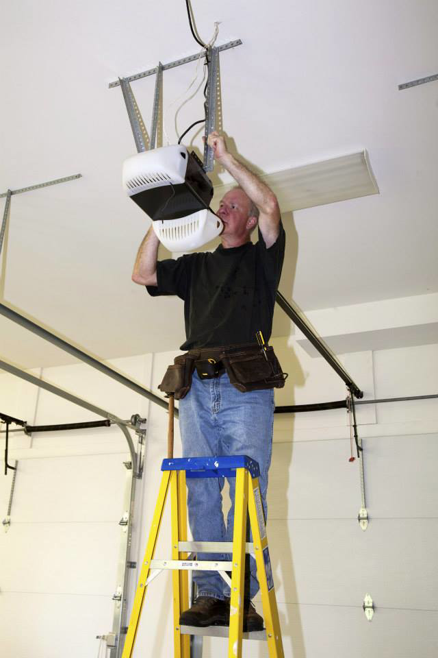 A technician repairing a garage door opener on a ladder, demonstrating a service by Integrity Garage Door Repair in Clearwater, FL.