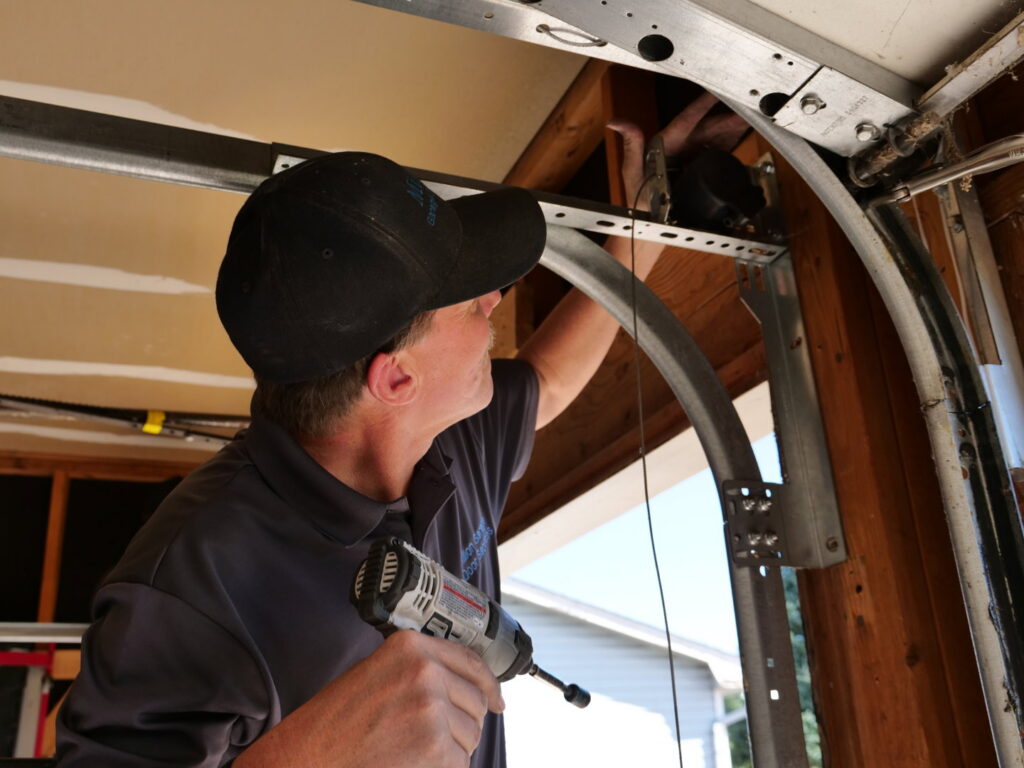 A Million Garage Door Services technician using a drill to repair a garage door opener mechanism in Colorado Springs, CO.